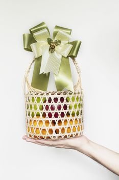 Hand showing fresh fruit souvenir in weaved bamboo package over white gray background - fresh fruit gift set for special occasion concept