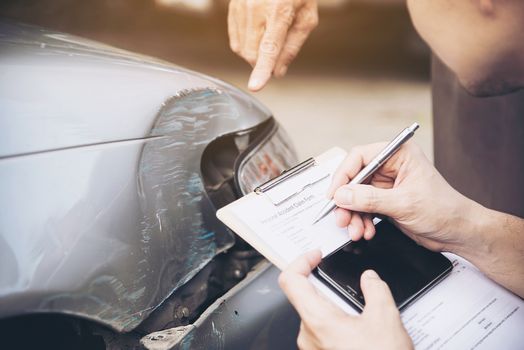 Insurance agent working during on site car accident claim process - people and car insurance claim concept