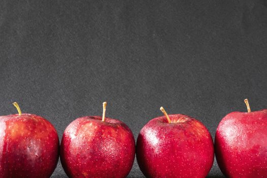 Fresh colorful apple with water drop on skin over gray background - clean fresh fruit background concept