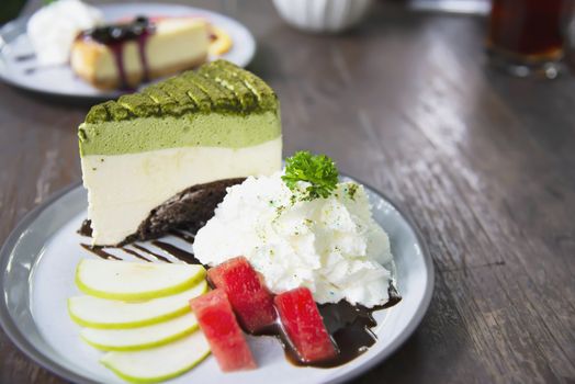 Colorful green tea favor cake with well decorated fruit pieces and whipped cream in white plate - cake recipe menu concept