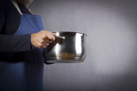 Pan in the hands of a man in an apron