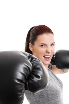 Close up shot of a young beautiful girl with boxing gloves punching the camera, isolated on white background.