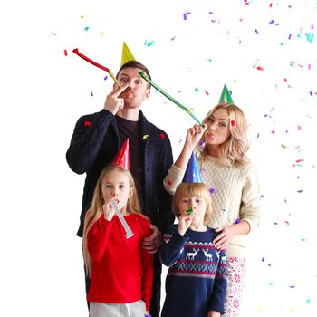 Family blowing party trumpets with confetti celebrating new year