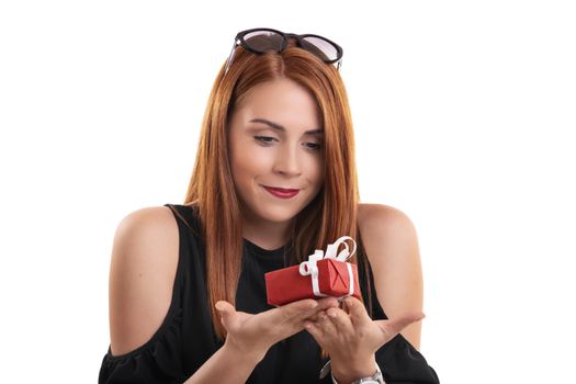 Portrait of a beautiful smiling girl holding a small wrapped gift box in both hands, isolated on white background. Christmas, New Year, Valentine’s gift concept.