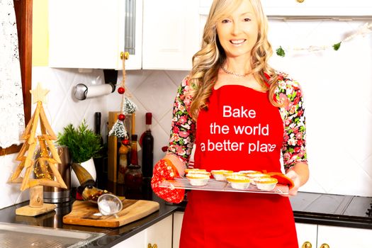 A happy smiling  woman with baked pastry pies in the kitchen at Christmas time