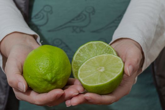 Woman holding green lemons and half lemons