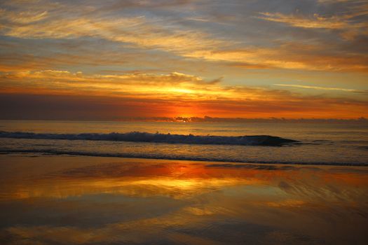 Colorful sunrise, clouds and reflections on the ocean.