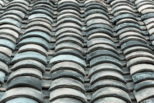 Close-up view curved clay tiled roof in various colors from an old house in North Vietnam, late afternoon light. Ancient, weathered roof tile surface, moss texture. Natural seamless pattern background