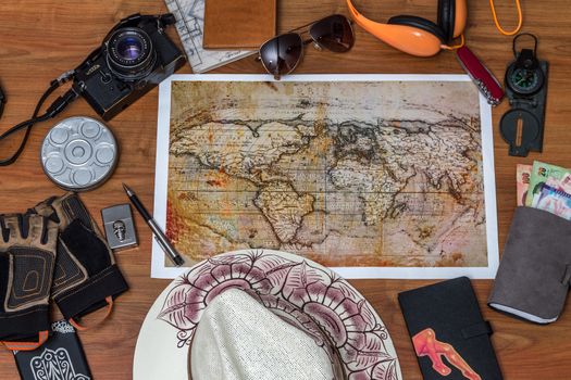 Man planning vacation using world map and compass along with other travel accessories. Tourist wearing brown hat looking at the world map