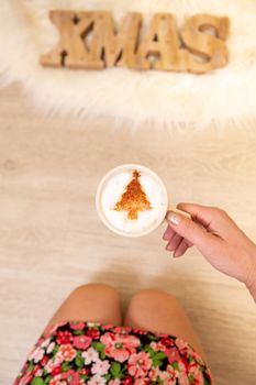 A festive coffee cappuccino decorated with Christmas tree in chocolate powder.  Cafe Christmas