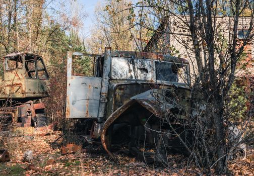 abandoned broken equipment car among trees in Chernobyl Ukraine in autumn