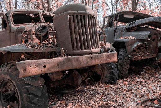 two abandoned rusty army trucks in the Chernobyl forest Ukraine