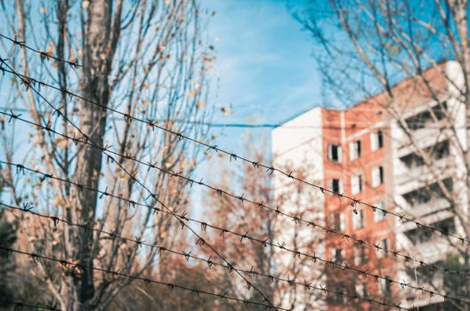 barbed wire fencing and cast and tree and blue sky with clouds house in Chernobyl Ukraine in the afternoon in autumn