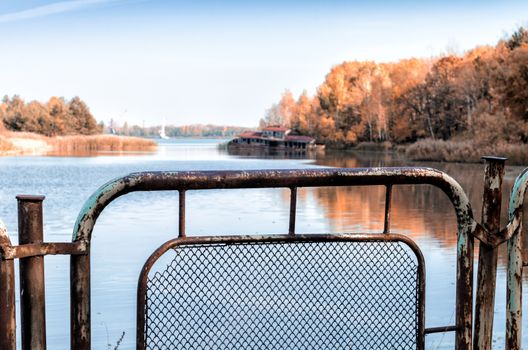 autumn landscape river and iron fence with a sunken destroyed house in Chernobyl in Ukraine
