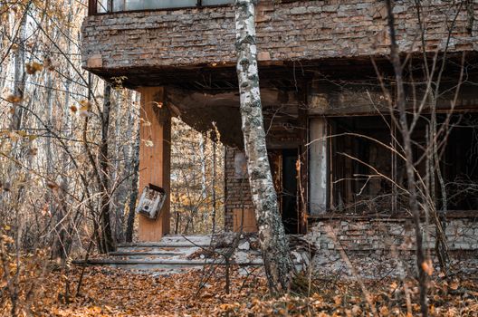 ruins brick house with broken windows and trees in the abandoned city of Chernobyl Ukraine in autumn