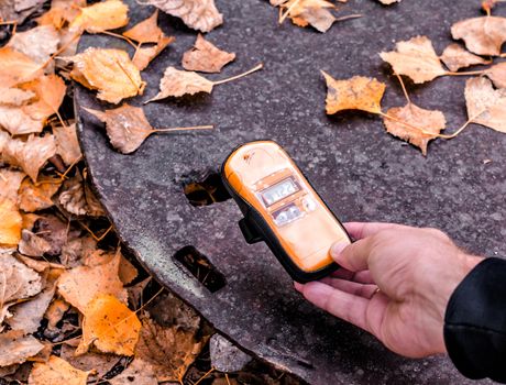 dosimeter device in a male hand near an infected radioactive iron object in Chernobyl Ukraine in autumn