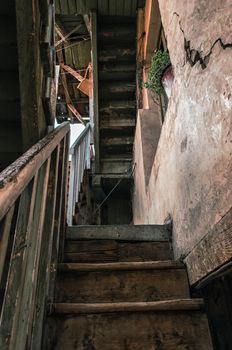 wooden steps of a staircase of an old vintage house with a crack in the wall and a green flower in the window in Georgia in Tbilisi