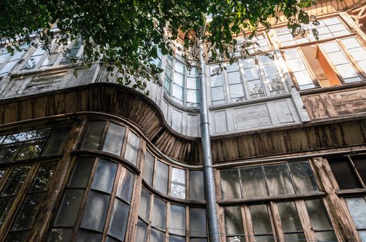 windows of old tall house with green leaves of tree branch in Tbilisi Georgia