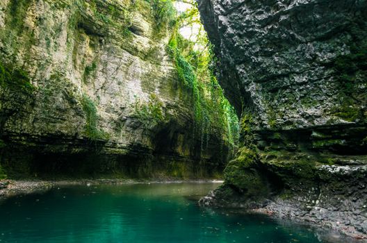 mountain river of high stone cliffs with green plants in the Martvili Canyon in Georgia in autumn