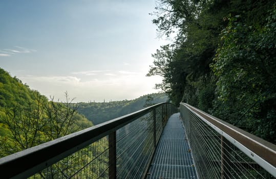 long safe tourist metal bridge in a canyon in Georgia in the fall against the backdrop of mountains and forest and sky with clouds