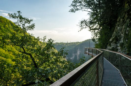 long safe metal bridge in canyon in Georgia in autumn against mountains and forests