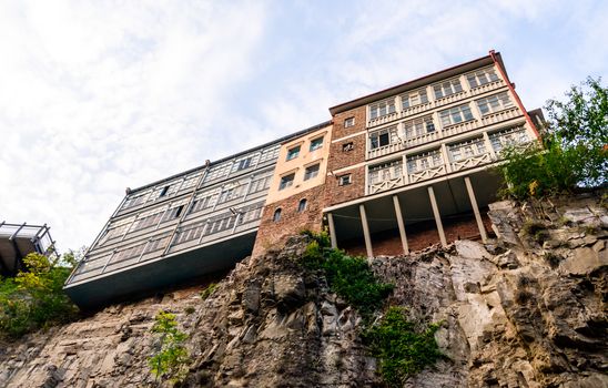 modern and old house high on a cliff against a sky with clouds in Tbilisi Georgia