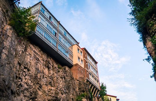 modern and old house high on a cliff against a sky with clouds in Tbilisi Georgia