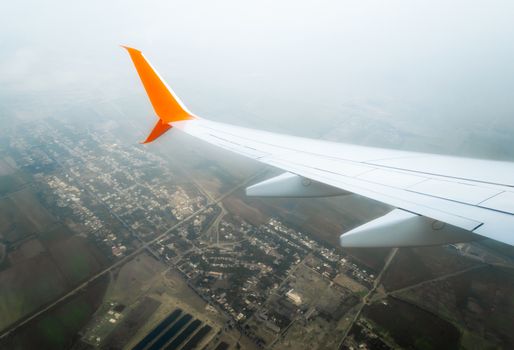 wing of a flying civil airliner over a city and fields Georgia Tbilisi