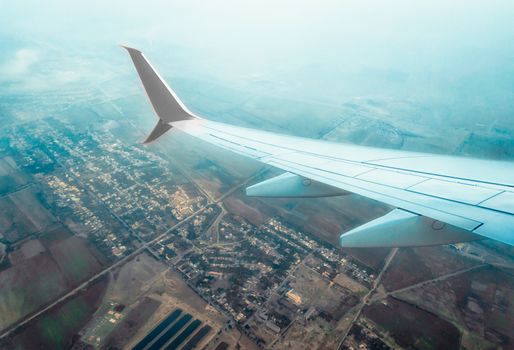 wing of a flying civil airliner over a city and fields Georgia Tbilisi