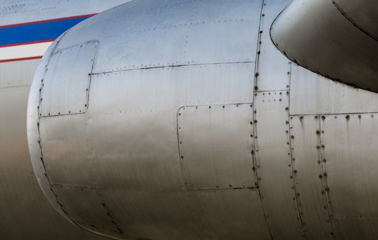background airplane body with blue and white stripe with turbine close up