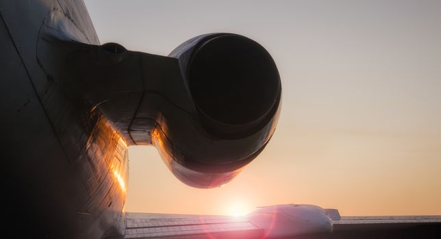 wing and turbine of a huge civilian airliner against the backdrop of sunset and glare of the sun