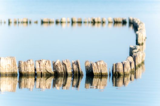 wooden posts in calm lake water in the afternoon autumn