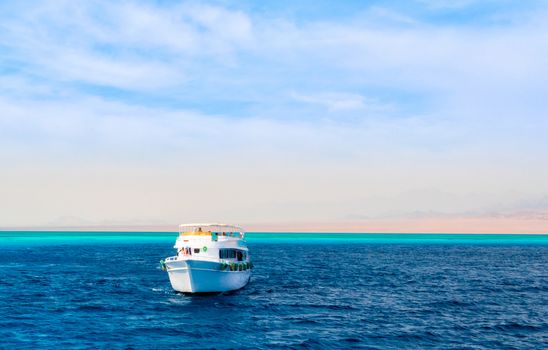landscape tourist boat in the Red Sea on the background of a rocky shore and blue sky and clouds in Egypt in Sharm El Sheikh