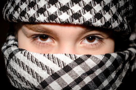 brown eyes of a young girl in arab black and white clothes close up