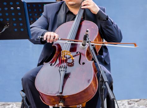 musician in blue suit playing the cello