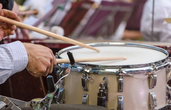 male musician drummer hands with drumsticks and drum closeup