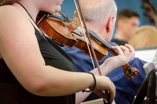 female musician playing a violin with a symphony orchestra