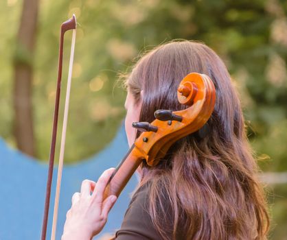 young brunette girl playing the cello on the street