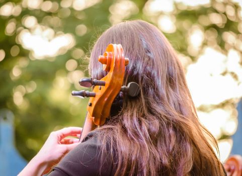 young brunette girl playing the cello on the street
