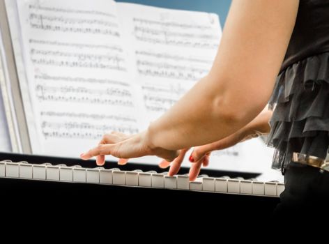female hands of a pianist musician and piano keys closeup