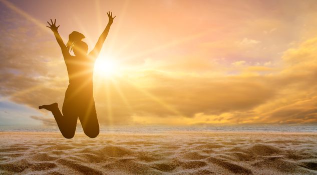 The girl is jumping with fun on the beach, the sea with the golden sun in the evening. summer concept