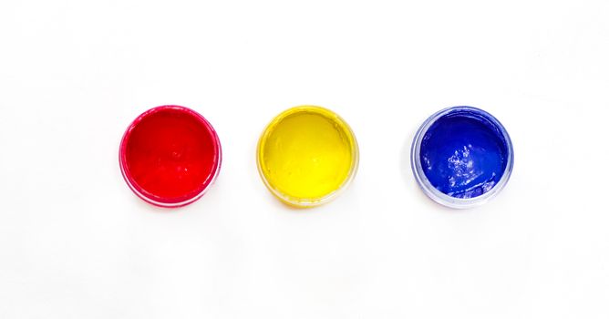 Gouache paint in containers isolated on white background. RGB colors of artistic paint. Red, yellow, blue.