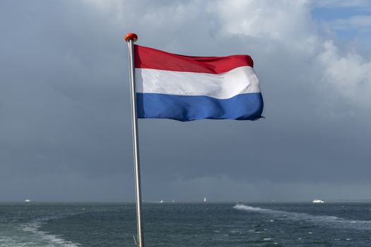 Wadden Sea with red white blue Dutch flag and ships in the background 
