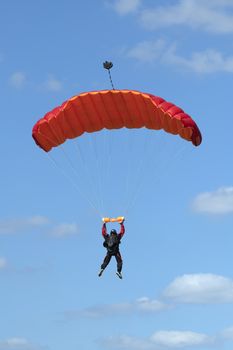Parachutist floating to a red square-shaped parachute
