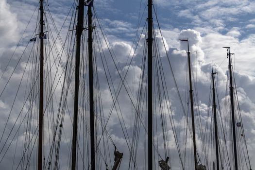 Masts in a harbor with impressive cloudy skies in the background in the North of the Netherlands
