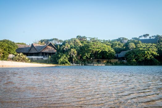 Traditional buildings in a forest by a lagoon on the Swahili Coast, Tanzania.