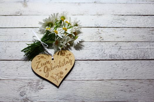 The picture shows happy birthday greetings on a heart with flowers