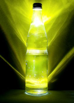 Bottle of mineral water behind yellow background. Healthy diet and healthy lifestyle. Cold water in a glass bottle with water drops on it.