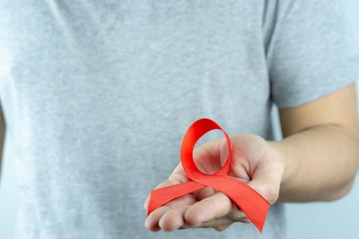 Aids awareness, male hands holding red AIDS awareness ribbon. World Aids Day, Healthcare and medical concept.