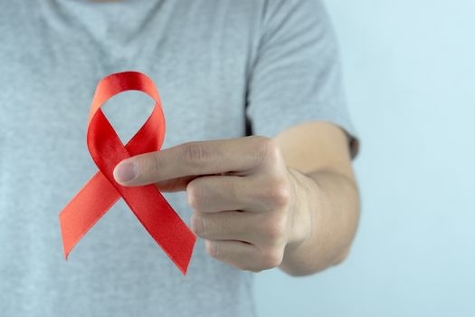 Aids awareness, male hands holding red AIDS awareness ribbon. World Aids Day, Healthcare and medical concept.